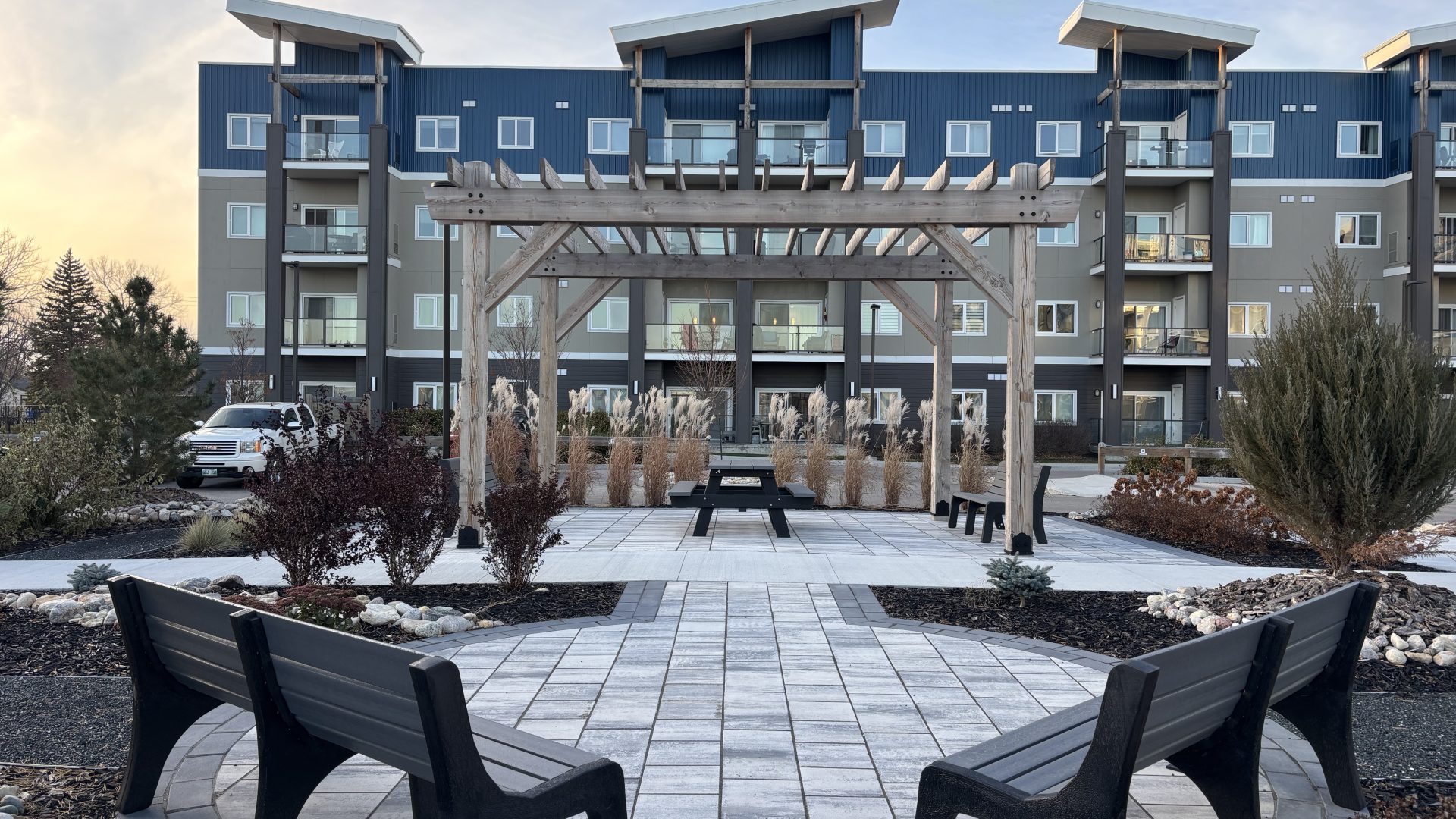 Limitless Landscaping softscaping and patio design in Winnipeg, Manitoba, featuring benches and a pergola.